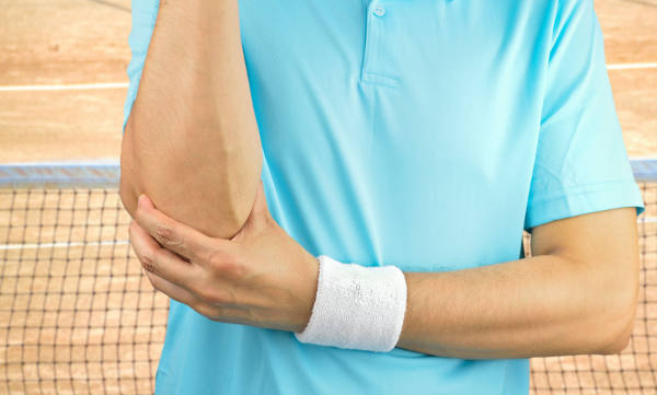 Shot of a tennis player with elbow injury on a clay court