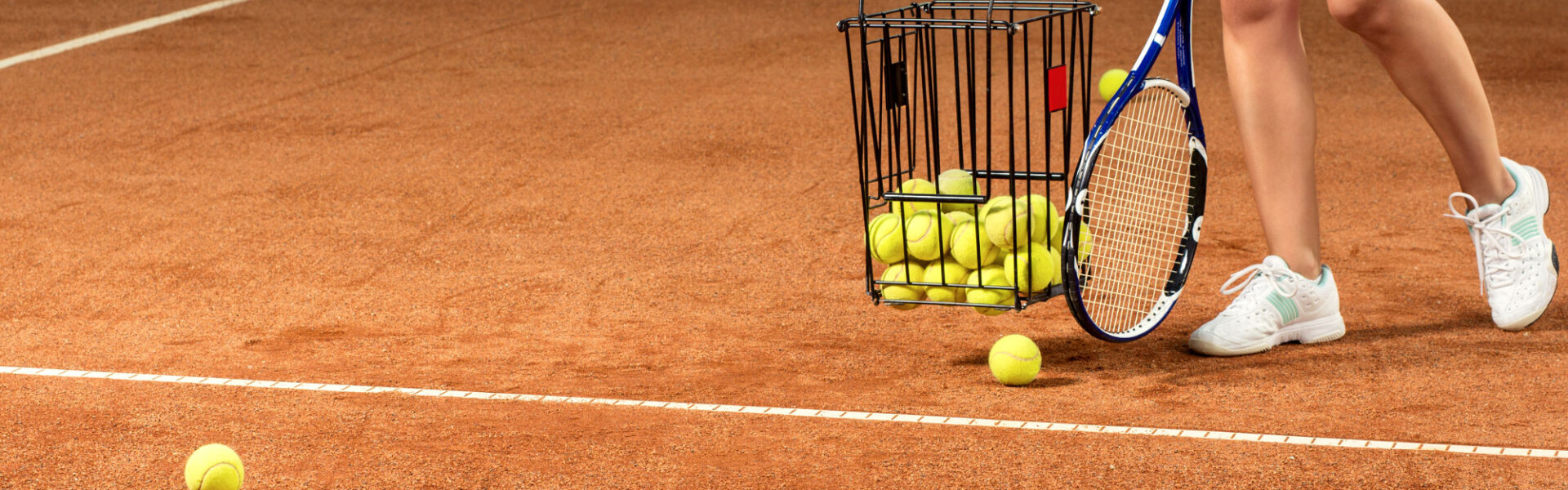 woman player gathering into basket tennis balls